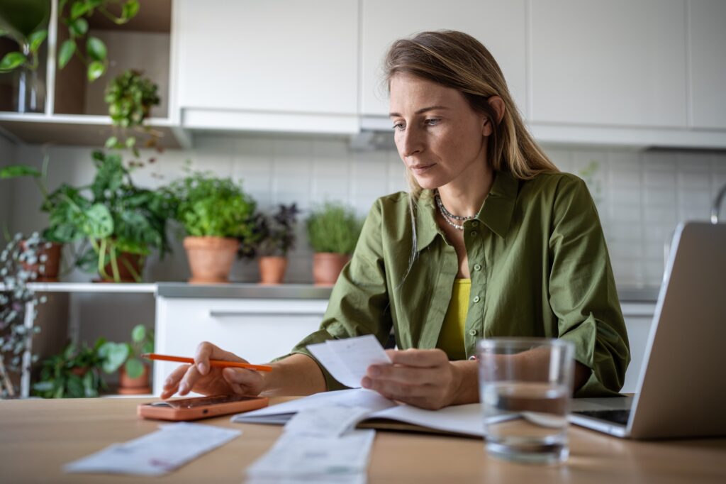 Financial literacy. Focused woman using phone calculating expenses trying to analyze domestic budget