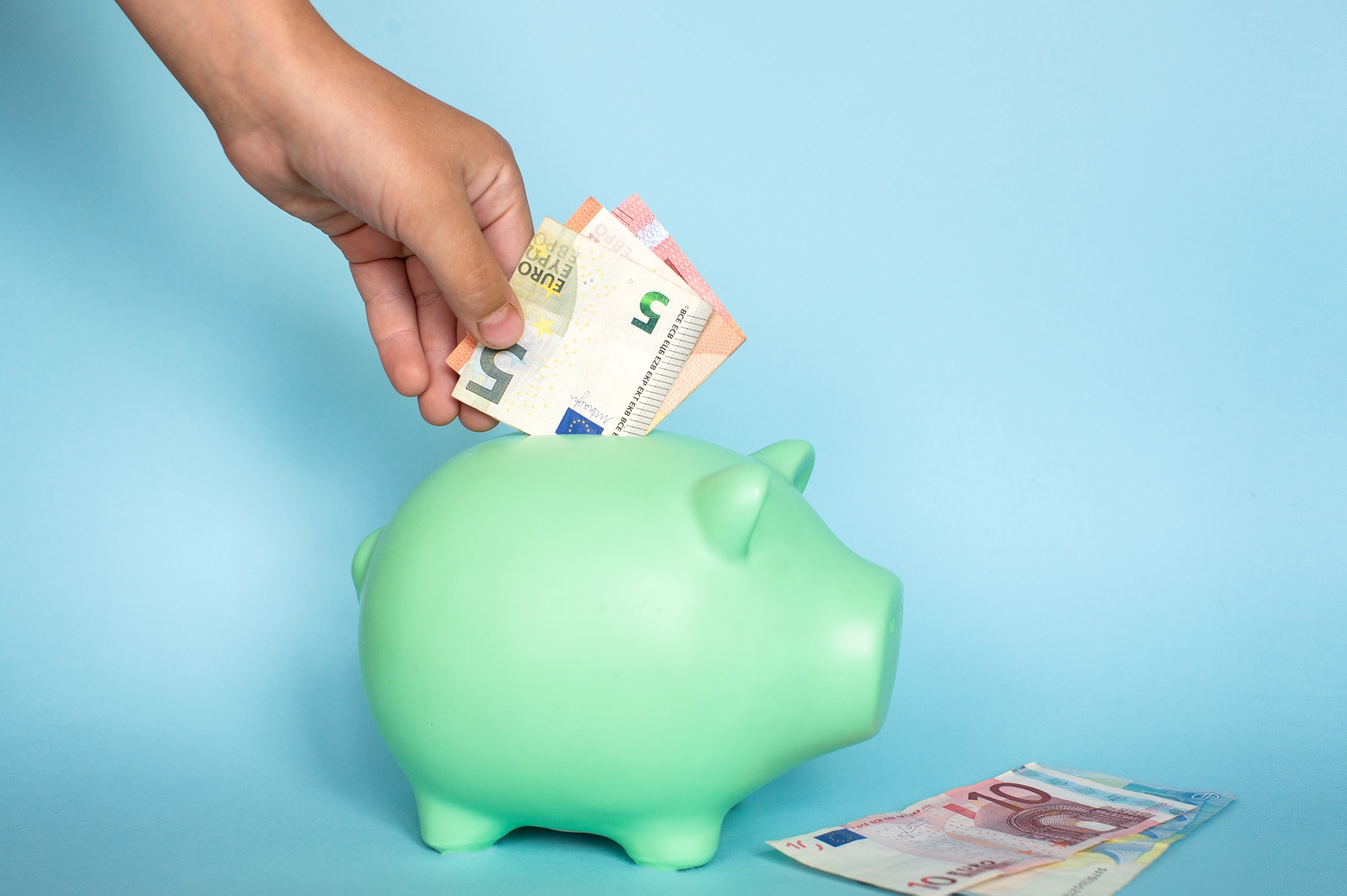 The boy puts the bill in the piggy bank. Teaching children financial literacy